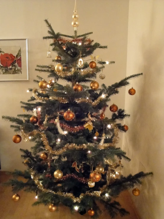 a small christmas tree with golden, silver, and gold ornaments