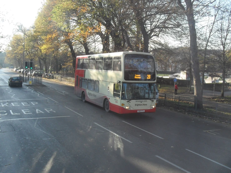 a white and red double decker bus going down the street