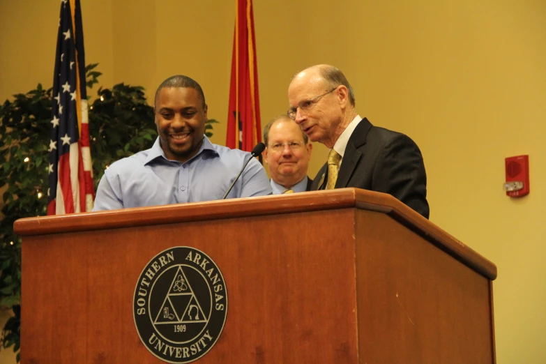 two men standing at the top of a podium