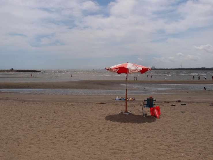 a lone person is standing on the beach under a sun umbrella