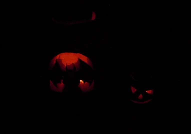 two pumpkins glowing and lit in the dark
