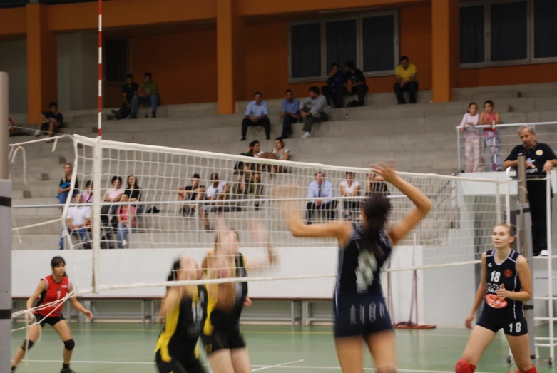 three women in blue and yellow uniforms are playing volleyball