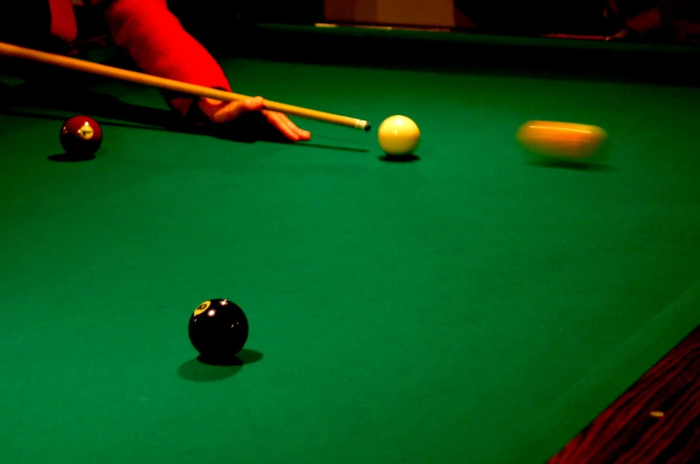 person in red shirt playing pool with black and white balls