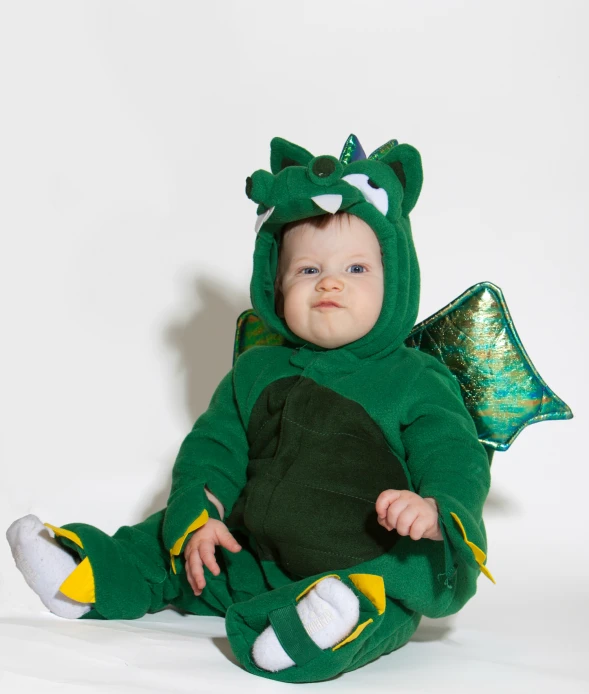 a baby is dressed up like a green dragon