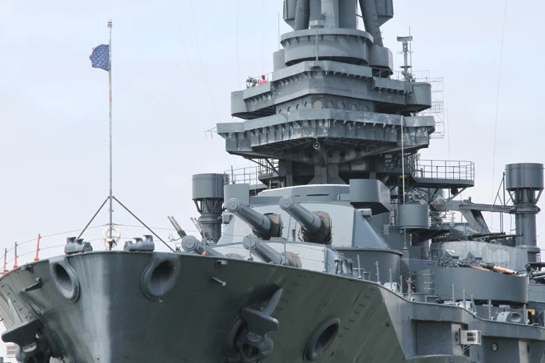 a large gray ship is next to a flagpole