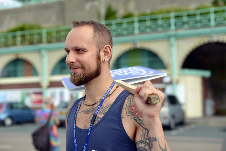 man with a beard carrying a board in a city