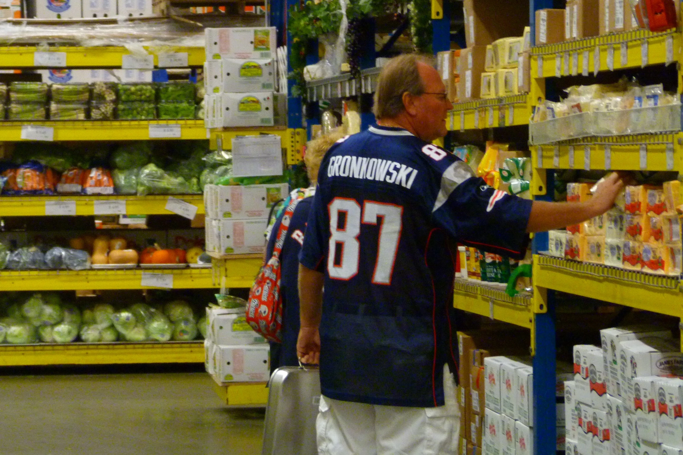 a man wearing a jersey walks along the aisles in a supermarket