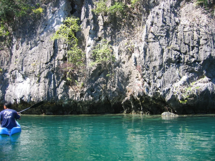 a man floating down the river next to a cliff