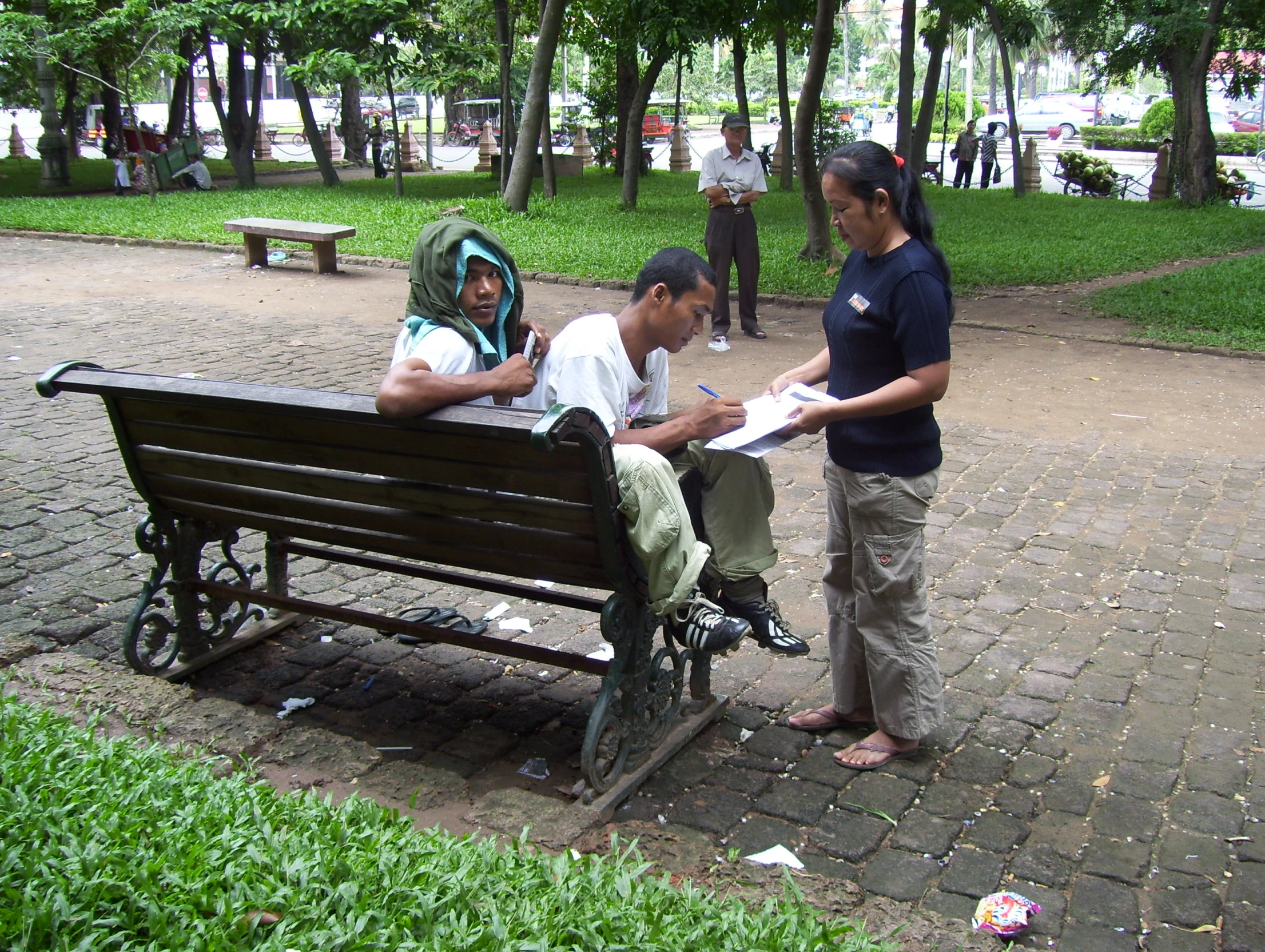 a couple of men and a woman sitting on a bench in a park