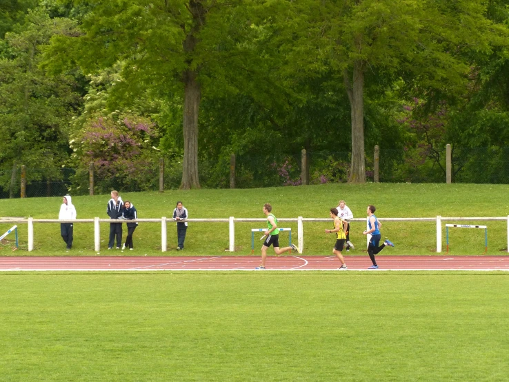 a man running on a race track while a group of people watch