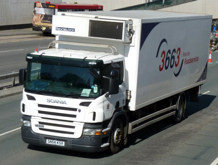 a white delivery truck is moving along the road