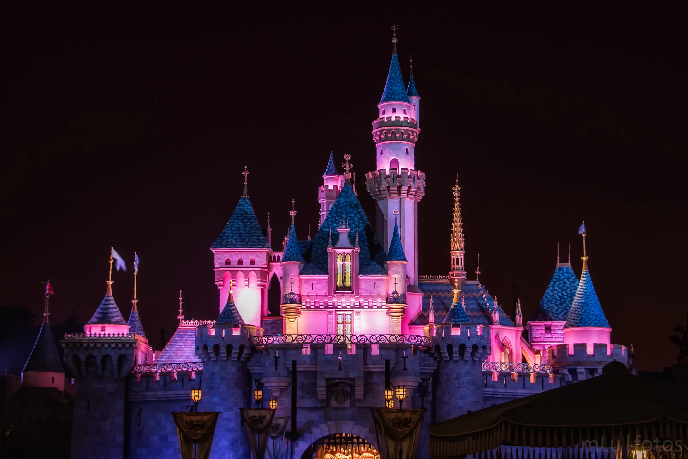 a view of a castle lit up in pink and blue