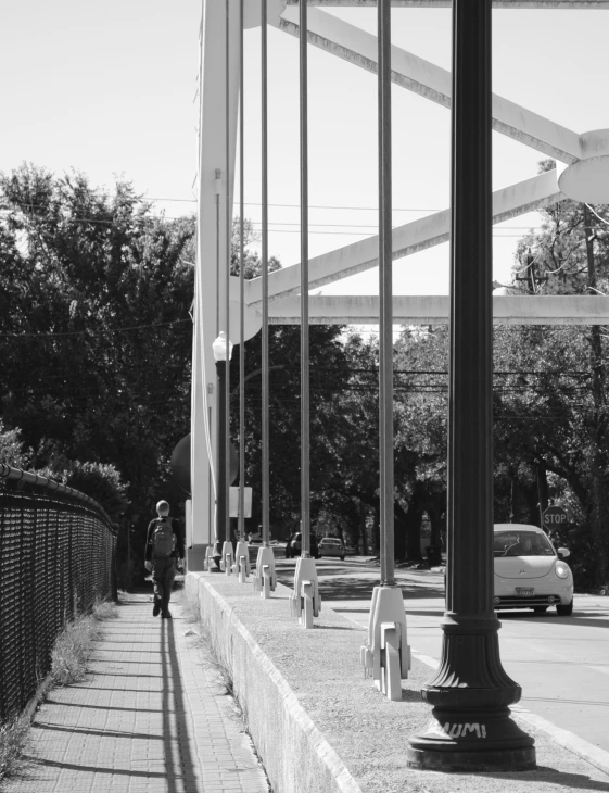 a black and white pograph of a person standing on the sidewalk