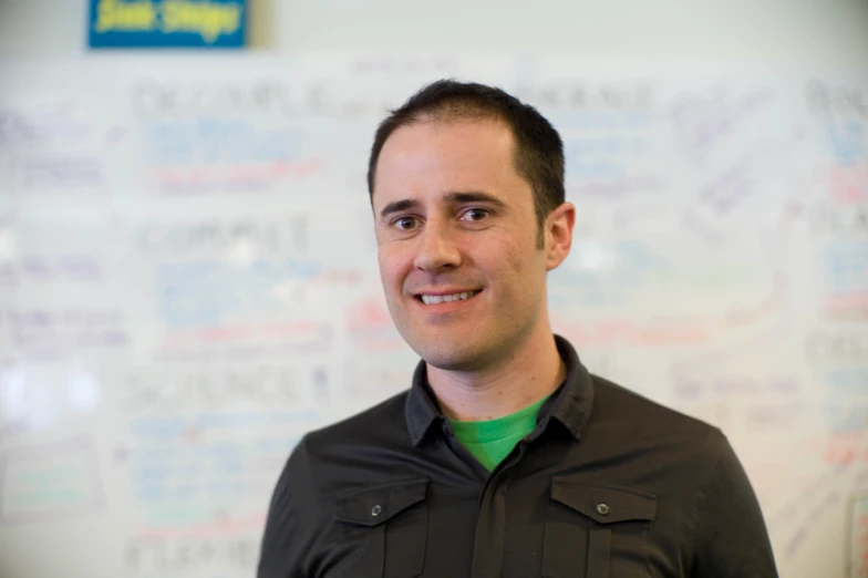 a man stands in front of a whiteboard with writing on it