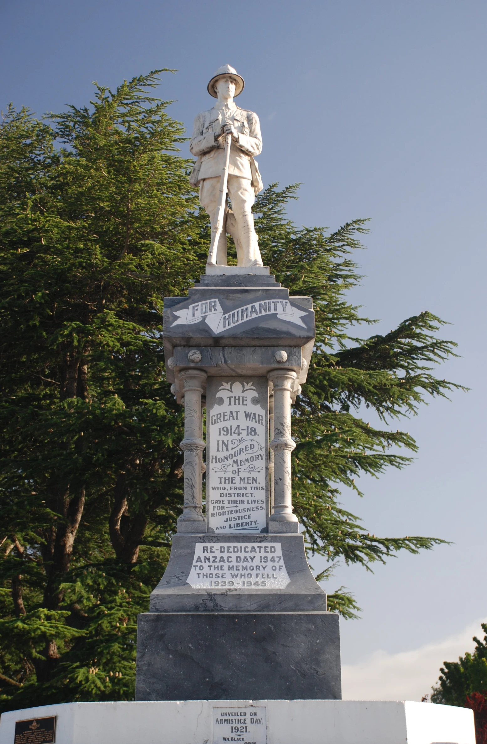 a white pole with writing on it surrounded by trees