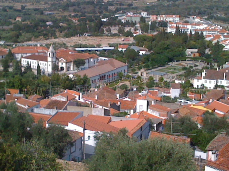 a city with red tiled roofs, in the middle of a forest