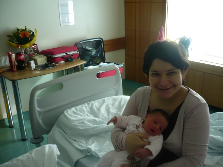 woman sitting on a hospital bed holding baby
