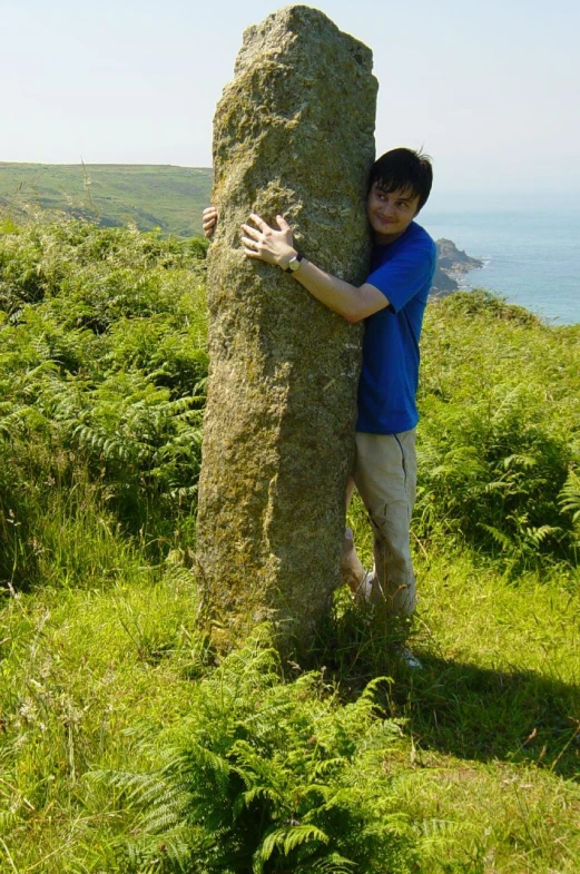 a young man holding onto the side of a large rock