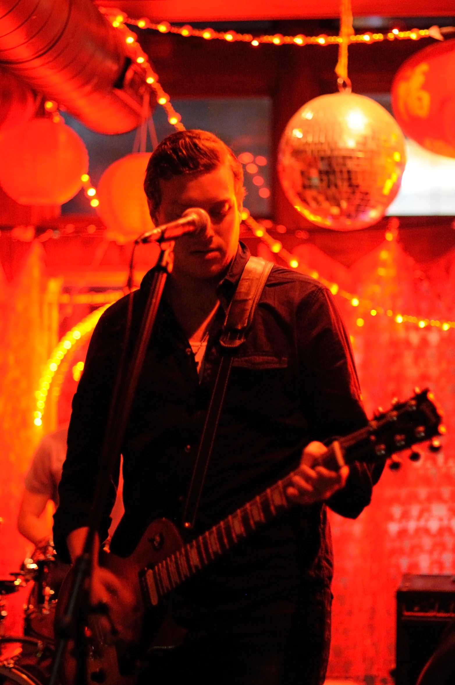 a man playing a guitar while singing into a microphone