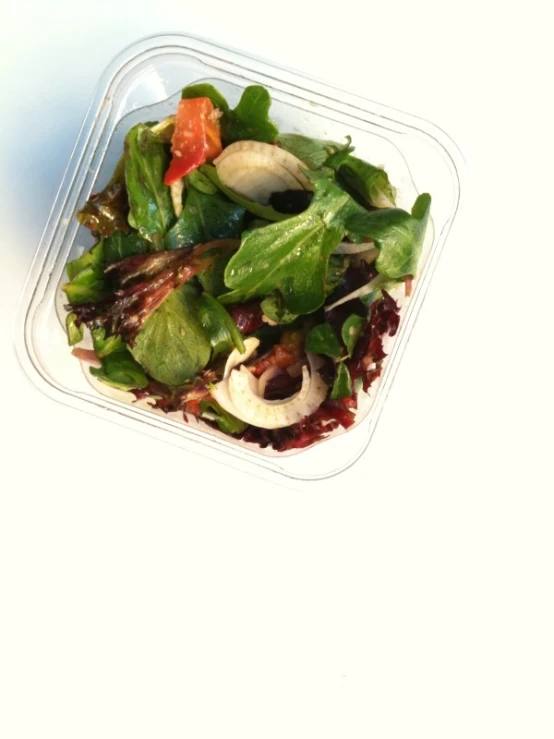 a salad inside of a plastic container on a table