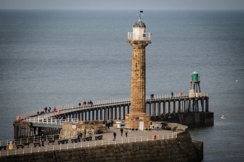 the tall light tower is on the pier next to the ocean