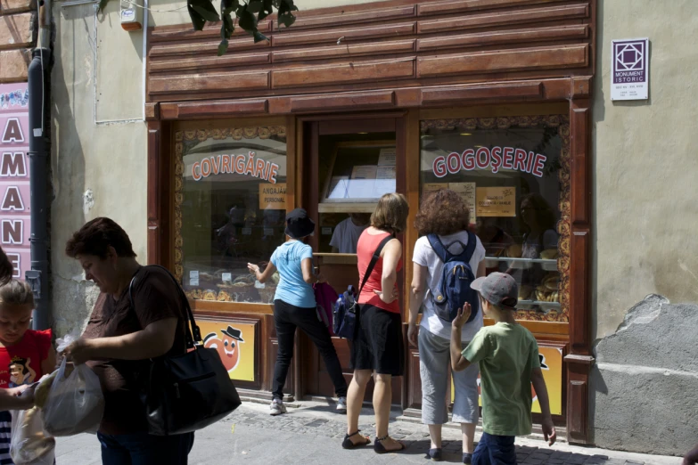 group of people stand around on sidewalk near store front