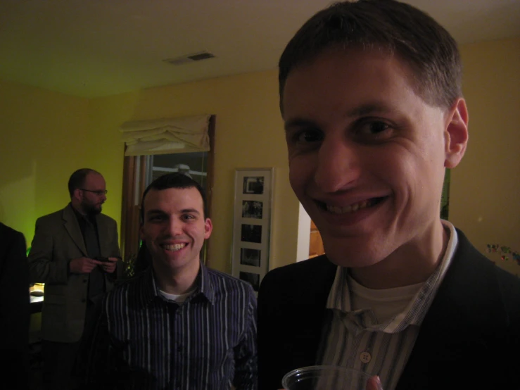 two men smile as they hold a glass