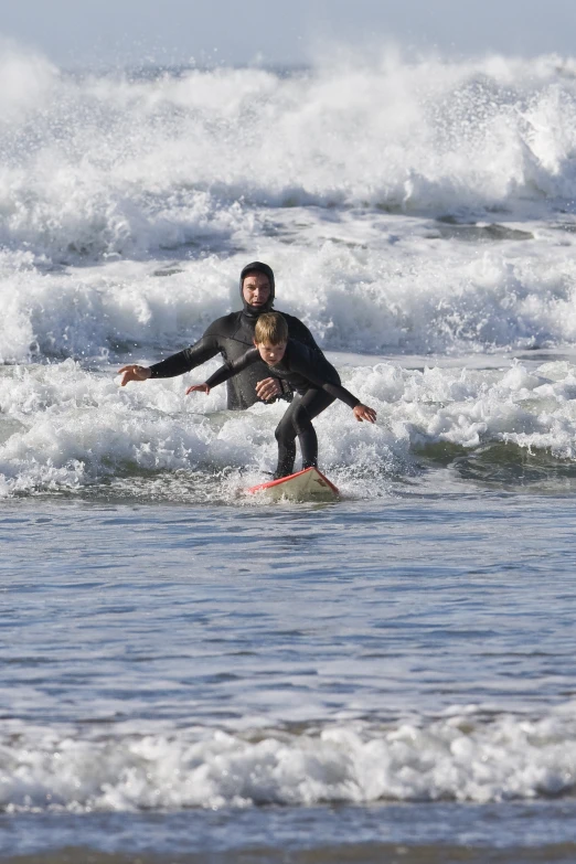 a man and a child are on a surfboard