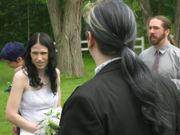 two brides wearing wedding gowns and a man with grey hair
