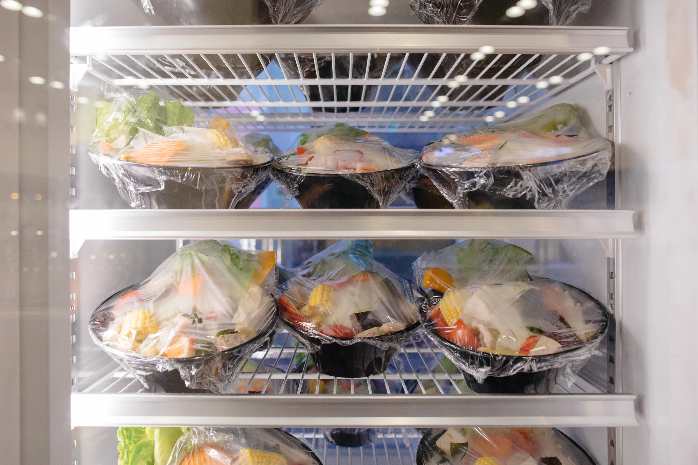 several trays of food are on display in a refrigerator