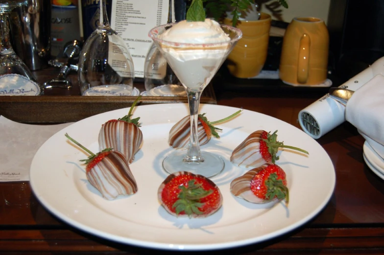 strawberries on a plate with milk, and a drink on the side