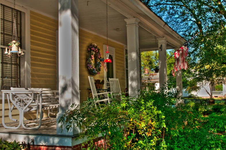 a porch with chairs, tree and flowers on it