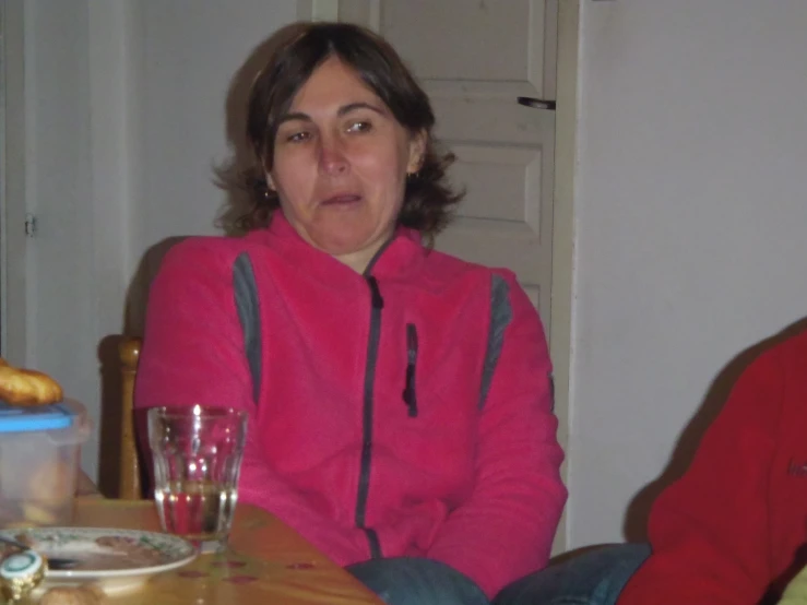 woman sitting at table with empty glass in front of her