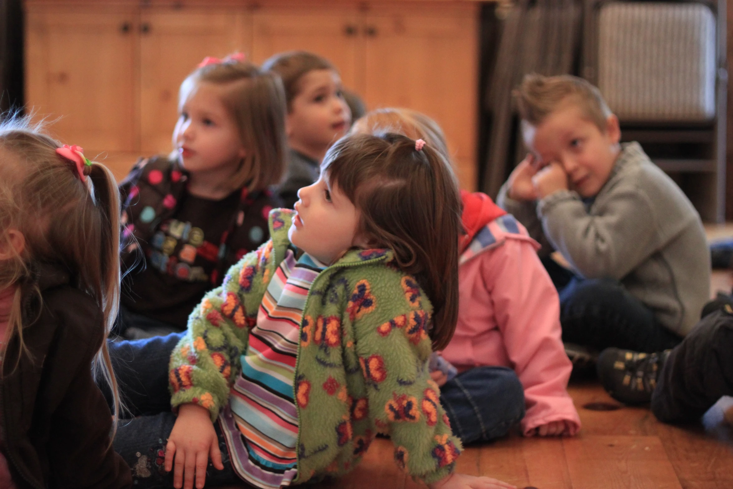 several children are sitting on the ground with their feet crossed