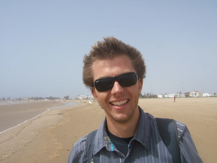 a man wearing sunglasses on the beach looking into the camera