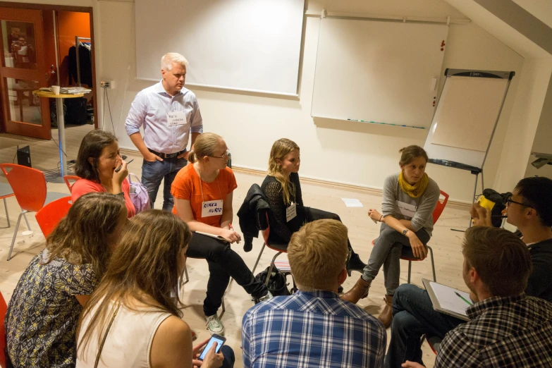 a group of people sitting around each other in front of a whiteboard