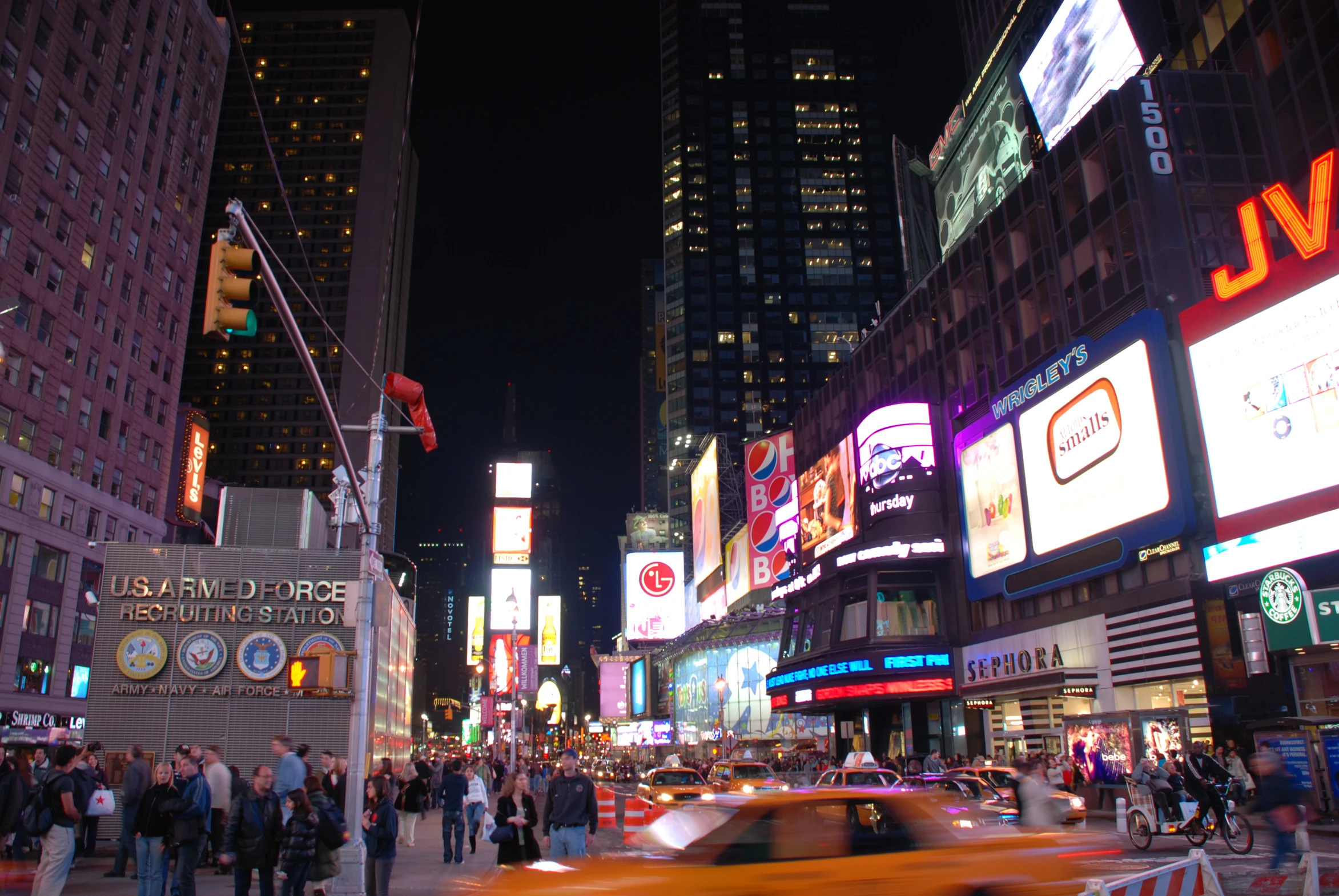 a busy city intersection at night with lights, cars, and people