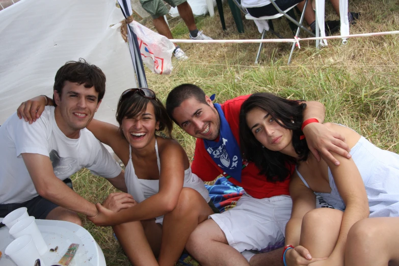 group of people sitting on grass with white tents behind them