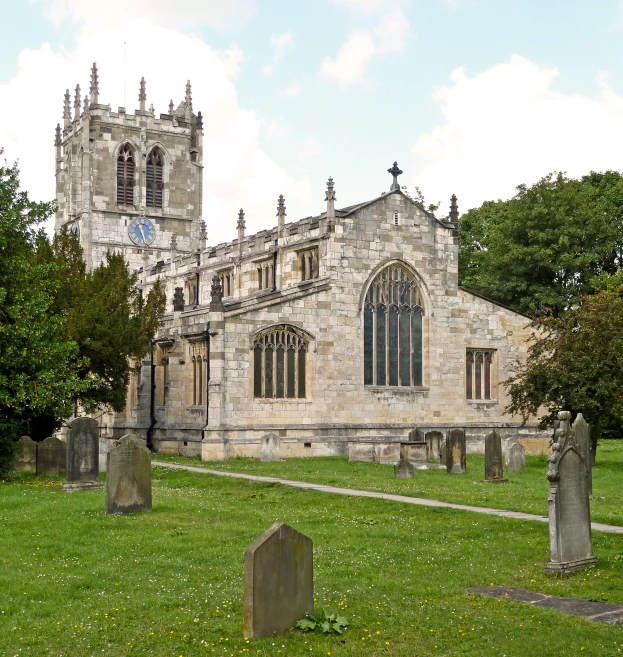 there is a gothic style church with graveyards on the grass