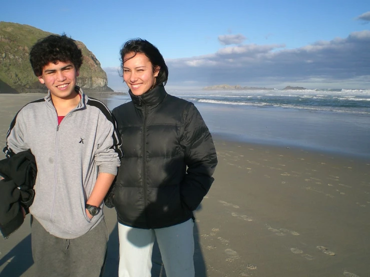 there are two people standing on the beach together