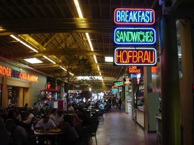 several signs advertising restaurants and walking through an indoor mall