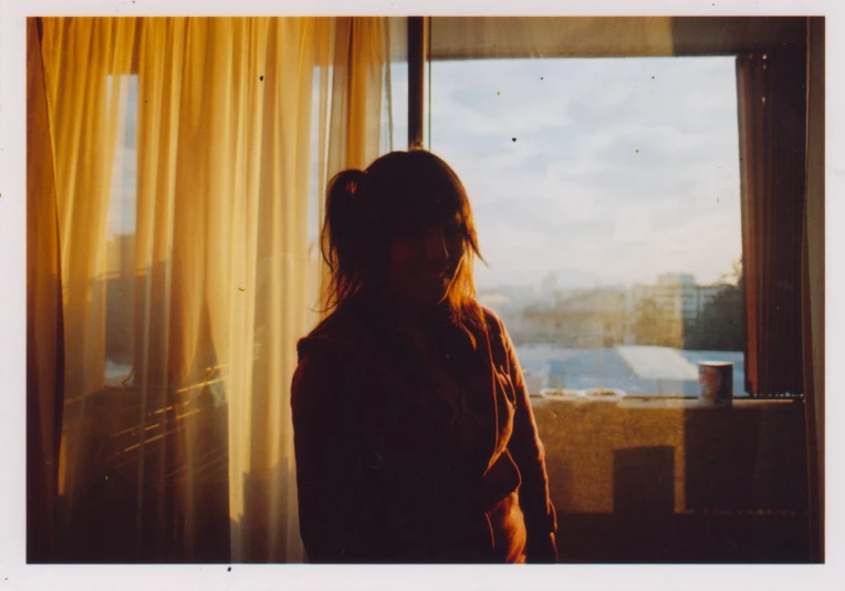 a woman standing by a window looking out at the city