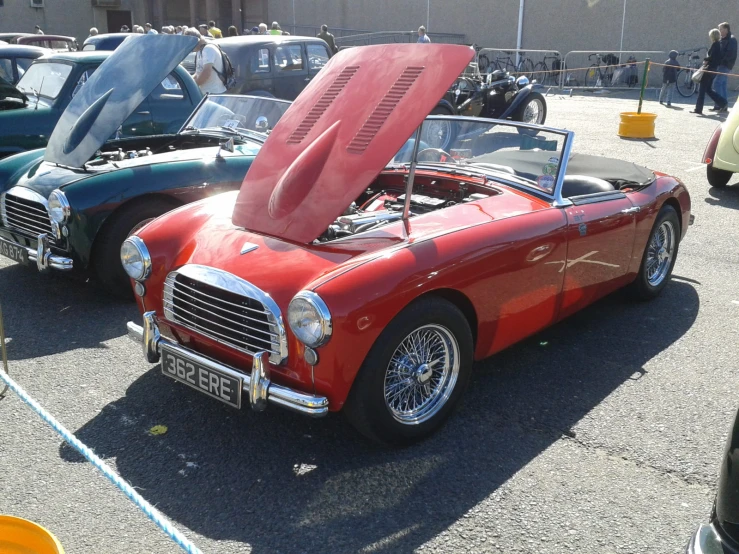 an old and used, red sports car is parked in the lot