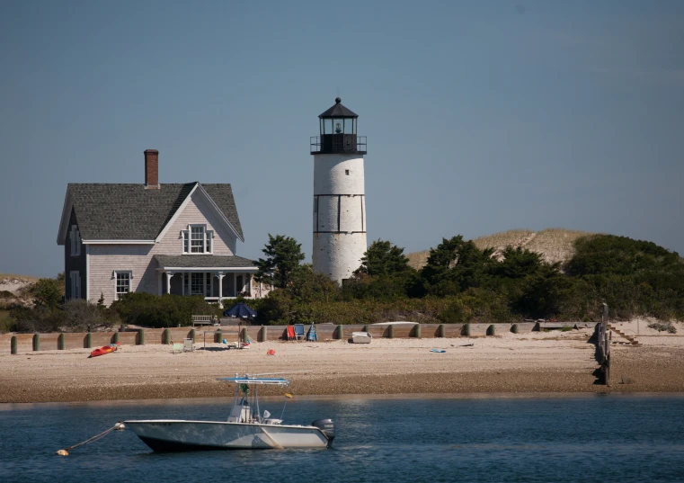 the lighthouse house stands over a beach with a boat