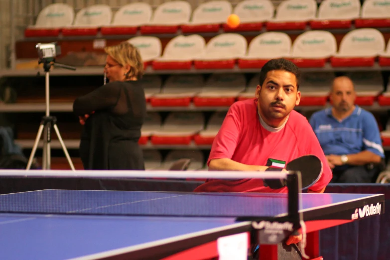 two ping pong players one is holding a racket and the other is looking at the ball