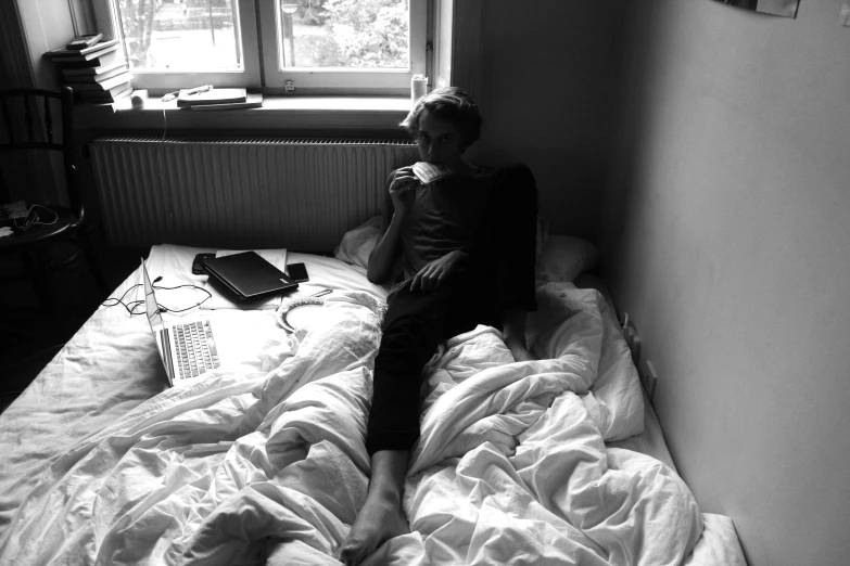 a woman is sitting on her bed looking off to the side