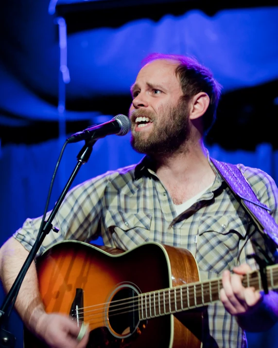 a man with a beard playing an acoustic guitar