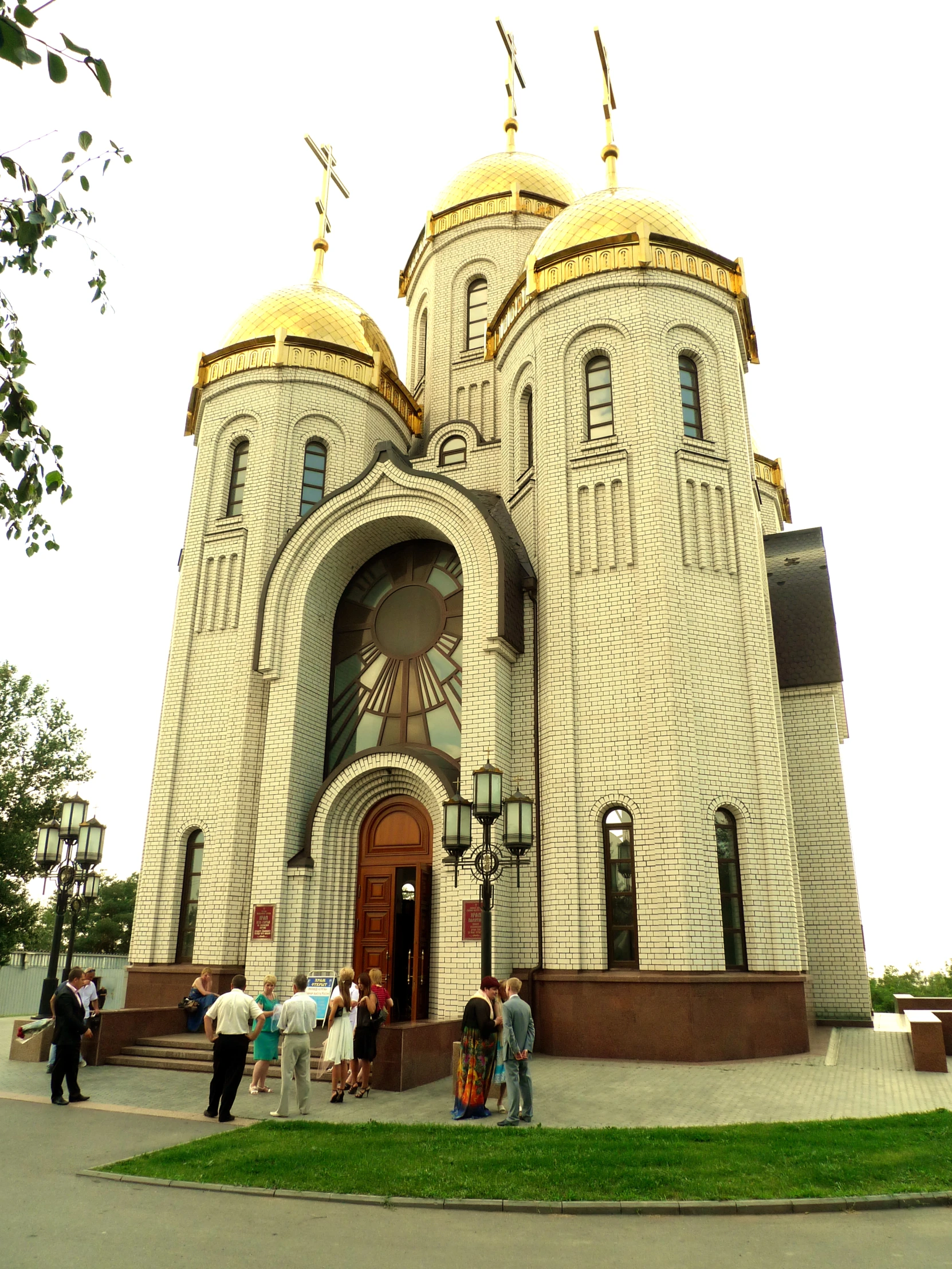 an artistic church with three golden domes in the daytime