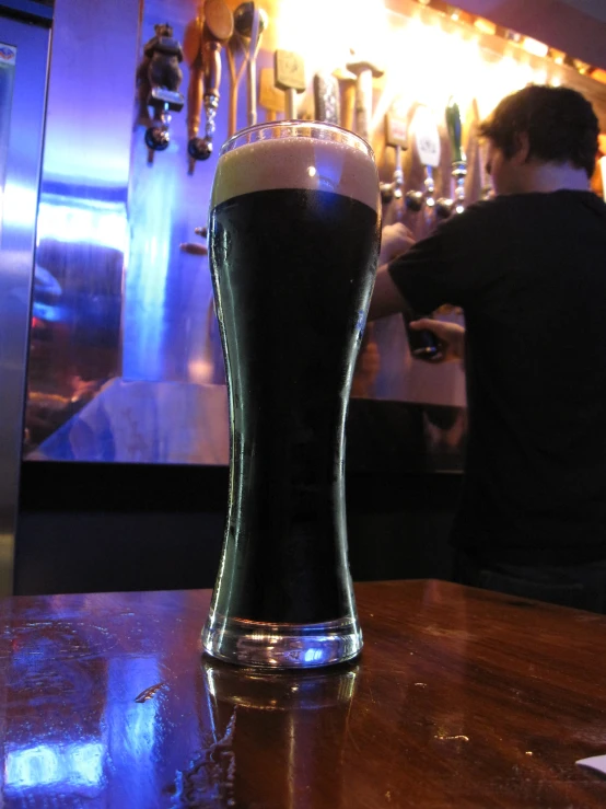 a tall glass with a dark beverage inside of it