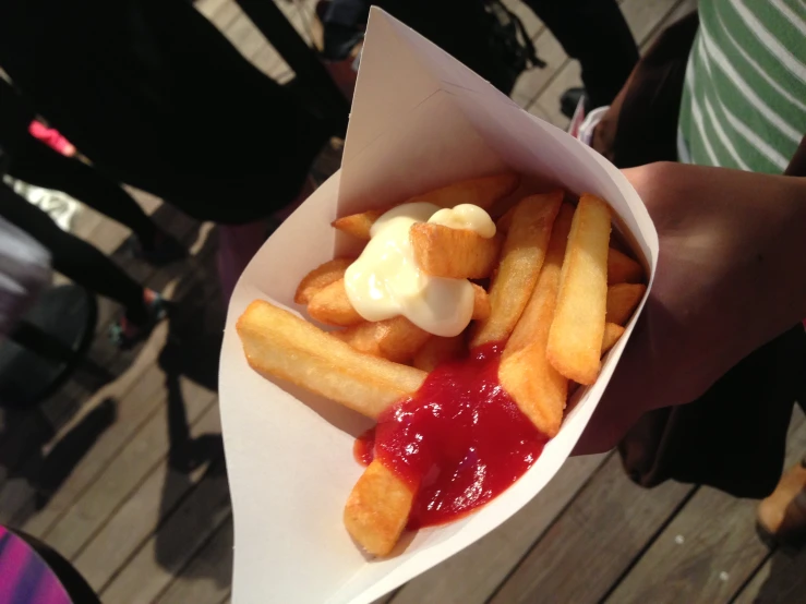 the french fries are covered with ketchup and a white substance